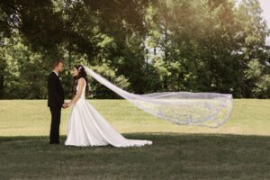 bride and groom holding each other with vail flying