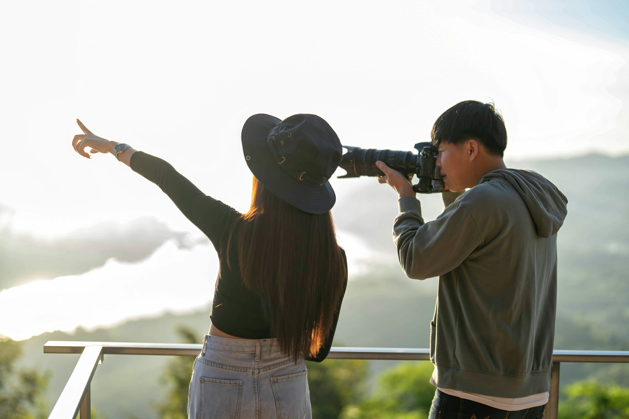 Sunrise morning traveler man hold camera zoom lens shooting beautiful girl on viewing platform